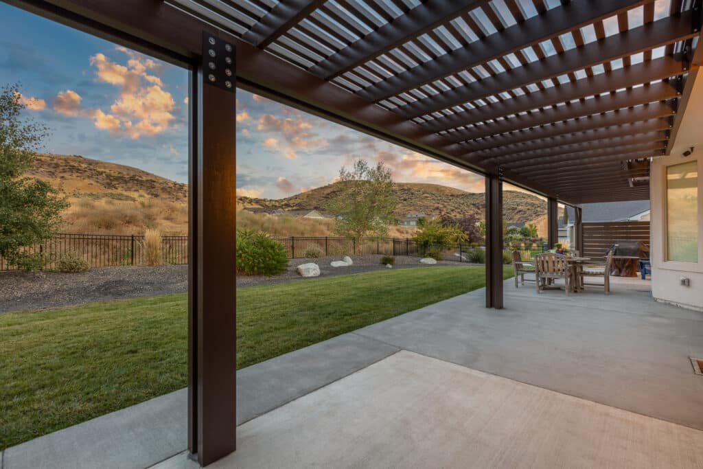 A brown pergola alongside a large home at the base of the foothills in Boise, Idaho.