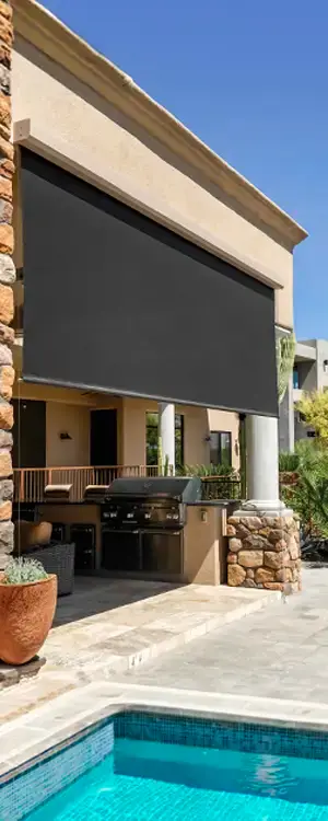 Motorized exterior patio screen installed for sun shade and privacy near poolside outdoor kitchen