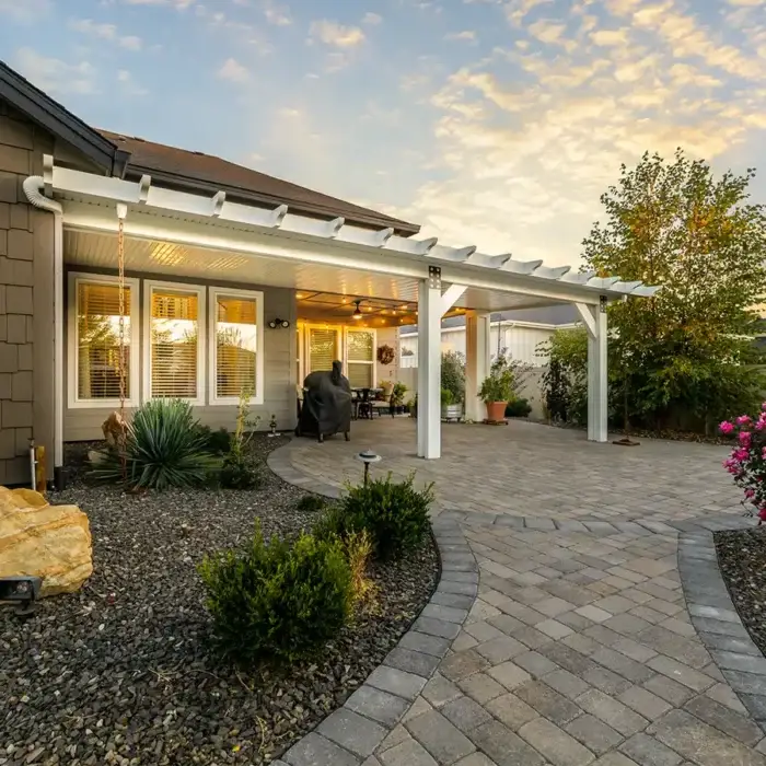 A patio cover connected directly to the house with visible roofline connection, posts, and an existing patio slab or seating area underneath.