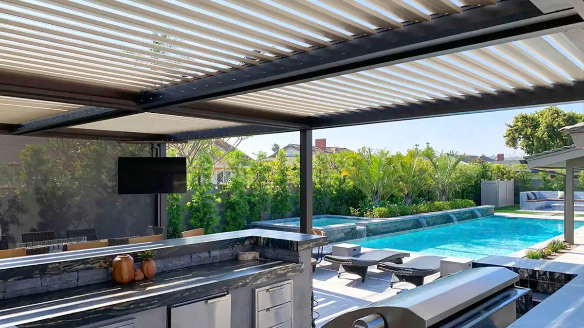 Louvered pergola covering outdoor kitchen and poolside entertaining area