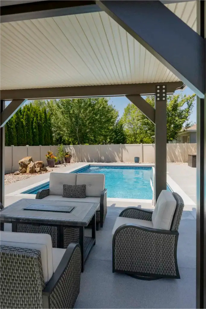 Covered Boise patio with outdoor seating area beside a pool, designed for shade, comfort, and protection from Idaho weather