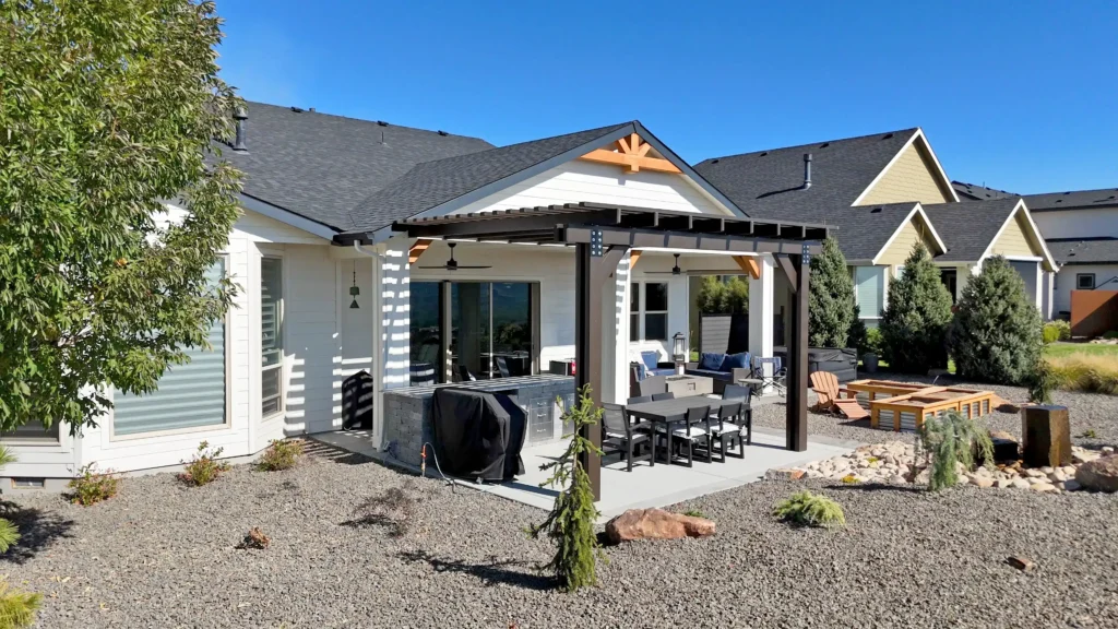 Custom attached pergola covering an outdoor dining and entertaining area behind a residential home