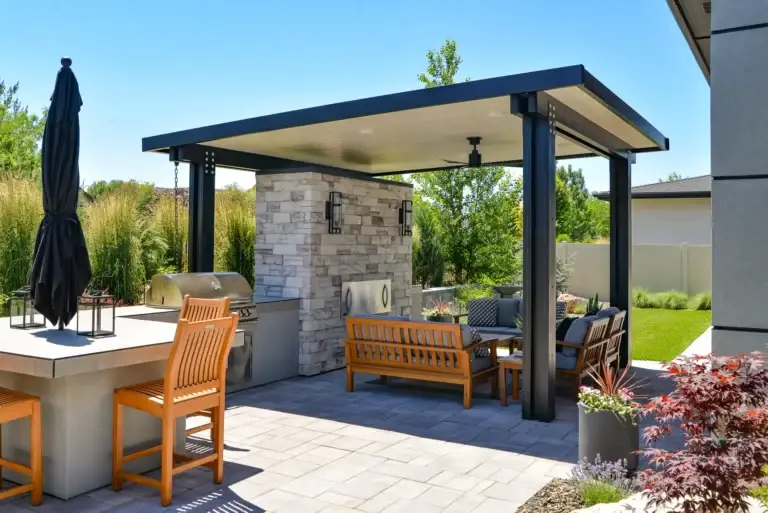 Freestanding patio cover beside an outdoor kitchen and fireplace