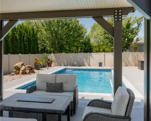 Covered Boise patio with outdoor seating area beside a pool, designed for shade, comfort, and protection from Idaho weather