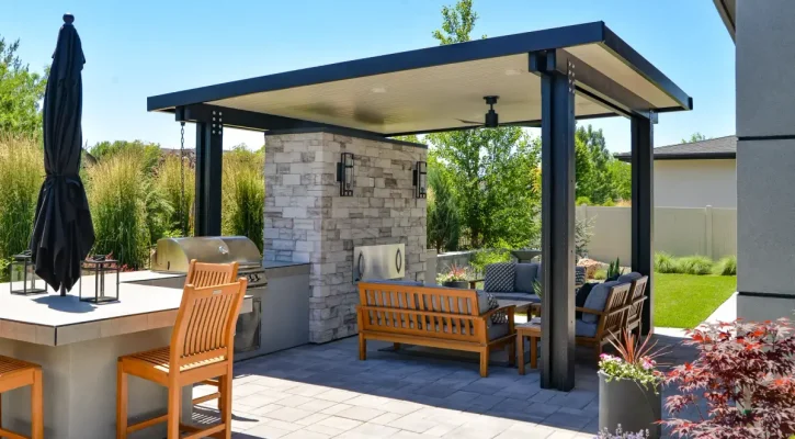 Freestanding patio cover beside an outdoor kitchen and fireplace