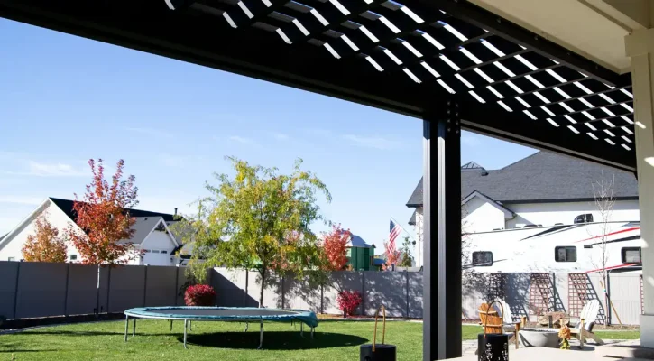 Sunlight filtering through pergola rafters creating shade pattern on patio