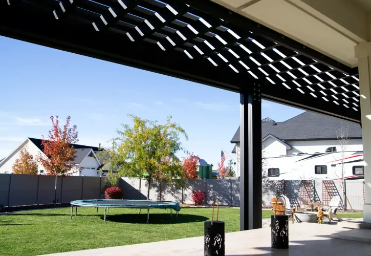 Sunlight filtering through pergola rafters creating shade pattern on patio