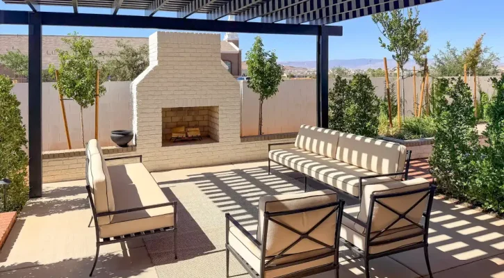 Custom black louvered pergola covering an outdoor living area with a fireplace, seating, and mountain views in St. George, Utah.