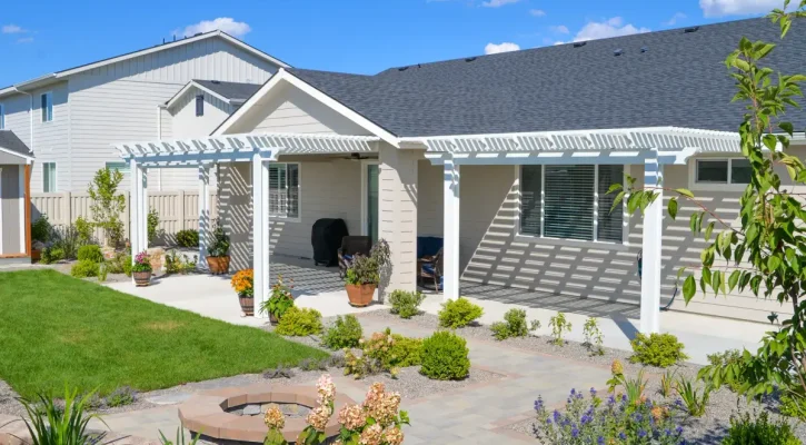 White aluminum pergola installed over a landscaped backyard patio