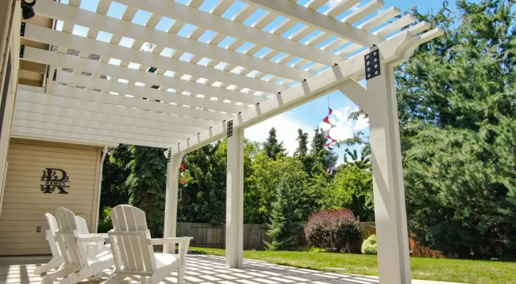 White aluminum pergola creating decorative shade over a backyard patio